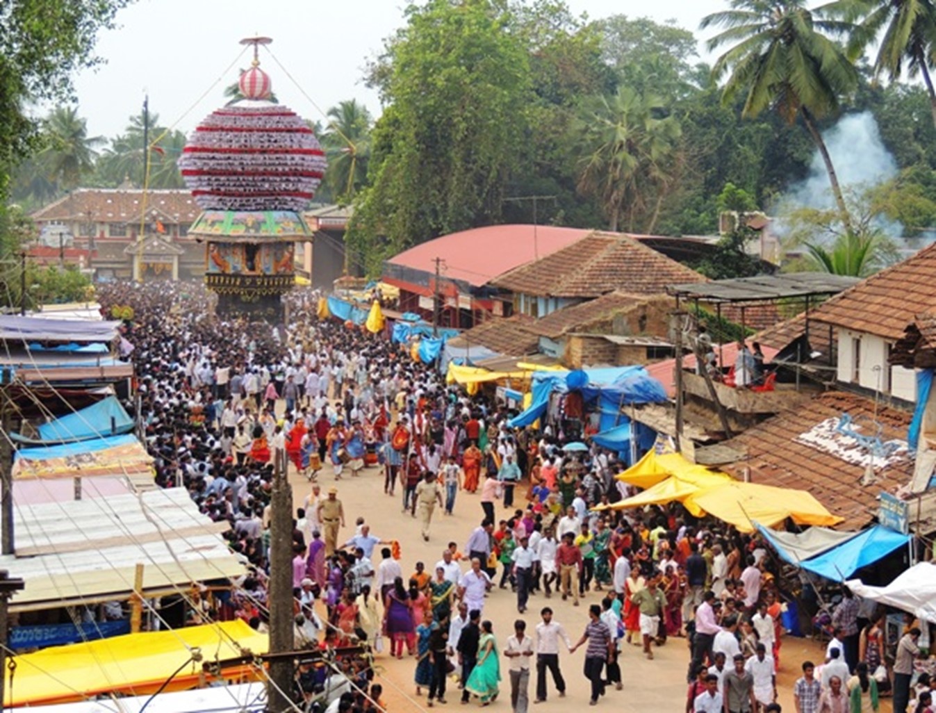 A vast crowd fills the temple street with market stalls as the festival chariot stands in the distance