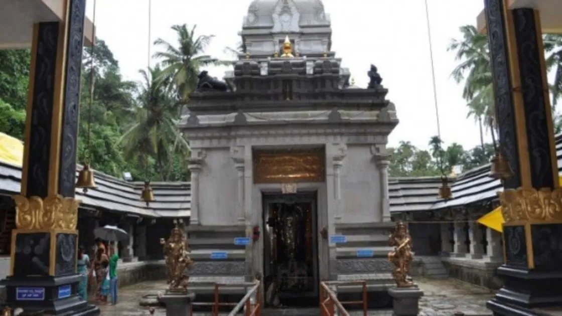 The grey stone sanctum and bell-lined courtyard of the Shankaranarayana temple after rain