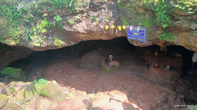 The low rock mouth of the Suparshwa Cave near Kamalashile, with a small shrine and offerings beneath the overhang